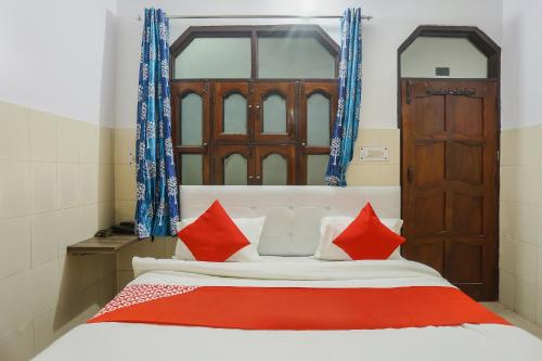 a bedroom with a bed with red and white pillows at Hotel O Gold Stayz in Ballabgarh