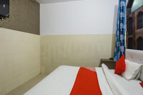 a bedroom with a bed with red and white pillows at Hotel O Gold Stayz in Ballabgarh