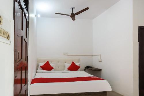 a bedroom with a white bed with red pillows at Hotel O Gold Stayz in Ballabgarh