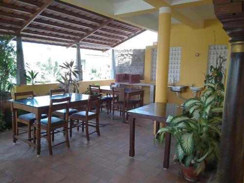 a restaurant with wooden tables and chairs and plants at Ram Guest House in Puducherry