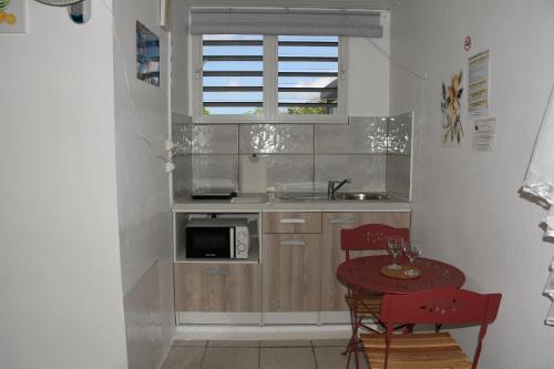 a small kitchen with a table and a microwave at O Logis du Morne Jacob "CITRON", Le Morne-Rouge Martinique in Le Morne Rouge