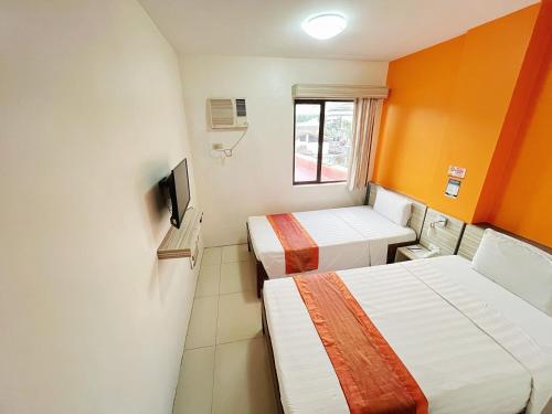 a small room with two beds and a window at Travelbee Business Inn in Cebu City