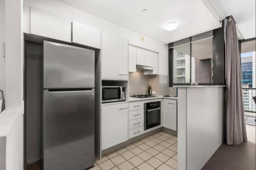 una cocina con nevera de acero inoxidable y armarios blancos en Open 1 Bedroom Apartment in Brisbane City, en Brisbane