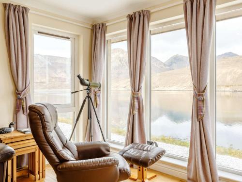 a living room with a chair and large windows at 3 Bed in Broadford 81181 in Luib