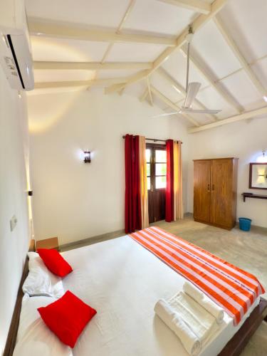a bedroom with a large white bed with red pillows at Sayuru Villa in Hikkaduwa