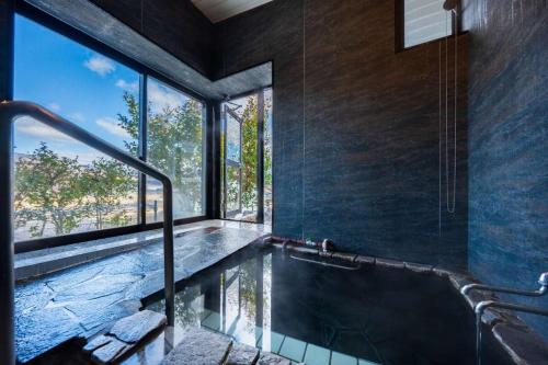 a bath tub in a room with a large window at 小景緑b栋 免費接送免費停車 拥有私人露天溫泉 与由布岳四季对望 in Yufu