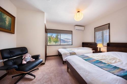 a bedroom with two beds and a chair with a stuffed animal at 小景緑b栋 免費接送免費停車 拥有私人露天溫泉 与由布岳四季对望 in Yufu