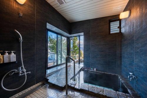 a bathroom with a tub and a shower with a window at 小景緑b栋 免費接送免費停車 拥有私人露天溫泉 与由布岳四季对望 in Yufu