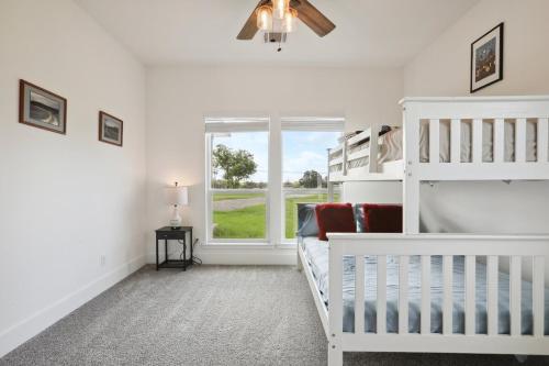 a white bedroom with a crib and a window at Modern Farmhouse in McDade in McDade