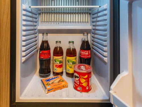 a refrigerator filled with cocacola drinks and snacks at Mercure Salzburg City in Salzburg