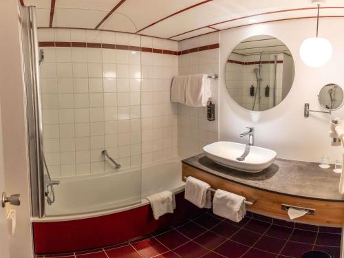 a bathroom with a sink and a tub and a mirror at Mercure Salzburg City in Salzburg