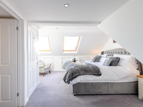 a white bedroom with a large bed and a chair at 4 Bed in Brockenhurst 80420 in Brockenhurst