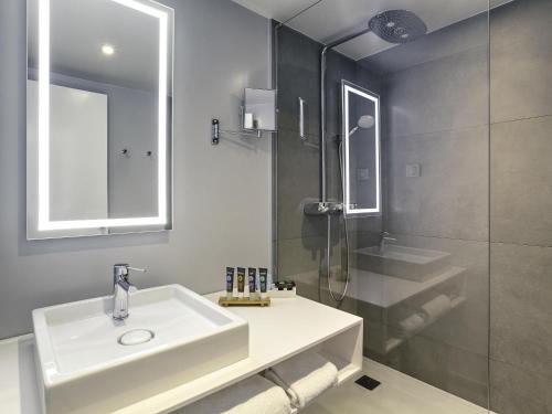 a bathroom with a white sink and a shower at Novotel Paris Charles de Gaulle Airport in Roissy-en-France
