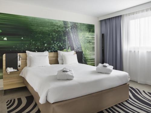 a bedroom with a large white bed with a green wall at Novotel Paris Charles de Gaulle Airport in Roissy-en-France