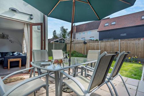 a glass table with chairs and an umbrella on a patio at Sparrows Nest Woodbridge in Martlesham