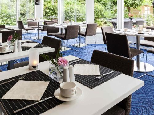 a dining room with white tables and chairs at Novotel Maastricht in Maastricht