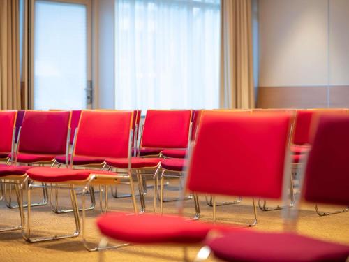 a group of red chairs sitting in a room at Novotel Maastricht in Maastricht