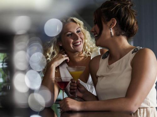 two women laughing while holding glasses of wine at Novotel Maastricht in Maastricht