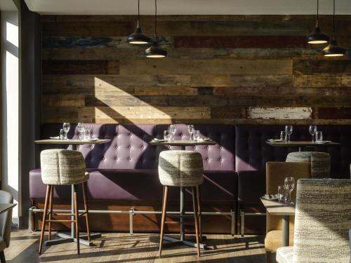 a restaurant with purple seats and a wooden wall at Novotel Ipswich Centre in Ipswich