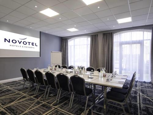 a conference room with a long table and chairs at Novotel Ipswich Centre in Ipswich