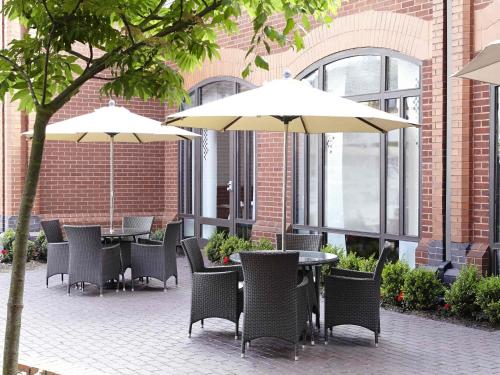 a group of tables and chairs with umbrellas at Novotel Ipswich Centre in Ipswich
