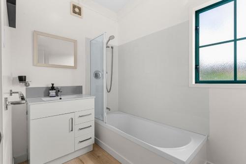 Waipu CoveにあるCove Family Haven - Waipu Holiday Homeのシャワーと洗面台を備えた白いバスルーム