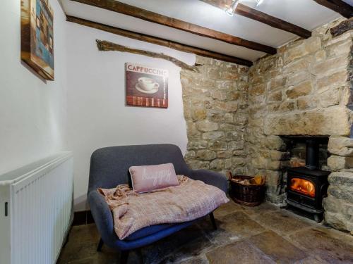a room with a chair and a stone fireplace at 3 Bed in Fritchley 85797 in Crich
