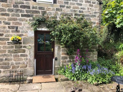 a brick house with a wooden door and flowers at 3 Bed in Fritchley 85797 in Crich