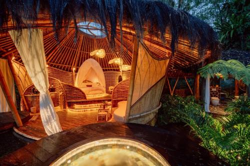 a room with a straw hut with a table and chairs at Hideout Eco Bamboo House Bali in Selat