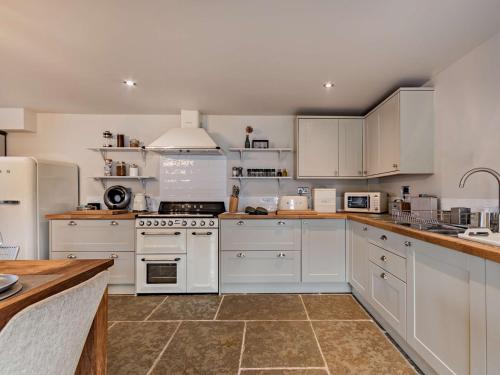 a kitchen with white cabinets and white appliances at 3 Bed in Melton Mowbray 61788 in Melton Mowbray