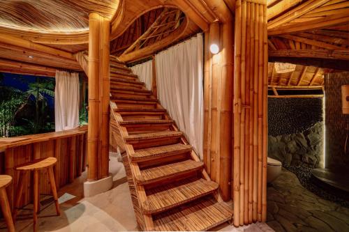 a wooden staircase in a room with a wooden ceiling at Hideout Eco Bamboo House Bali in Selat