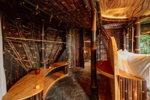 a room with a bed and a wooden bench at Hideout Eco Bamboo House Bali in Selat