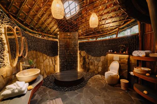a bathroom with a shower and a sink and a toilet at Hideout Eco Bamboo House Bali in Selat