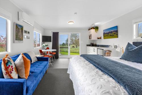 a bedroom with a large bed and a blue couch at Matamata Lodge in Matamata