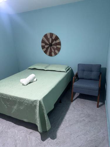 a bedroom with a bed and a blue wall and a chair at House in Itacaré in Itacaré