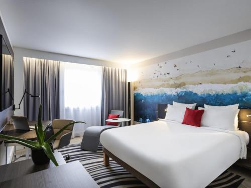 a hotel room with a large white bed and a couch at Novotel Bordeaux Centre Ville in Bordeaux