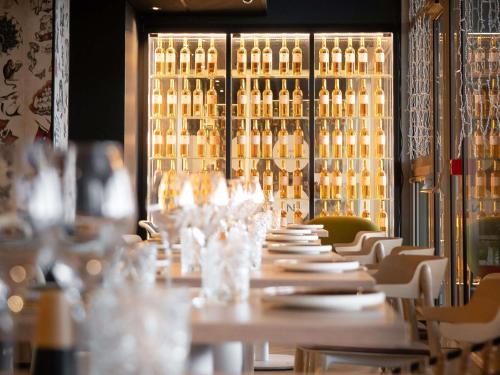 a long table in a room filled with bottles of wine at Novotel Bordeaux Centre Ville in Bordeaux