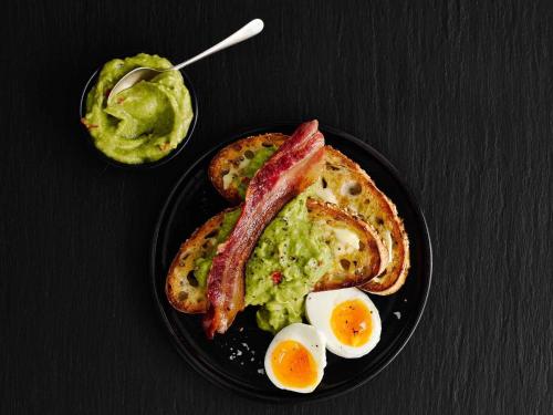 a plate of breakfast food with eggs bacon and toast at Ibis London Luton Airport in Luton
