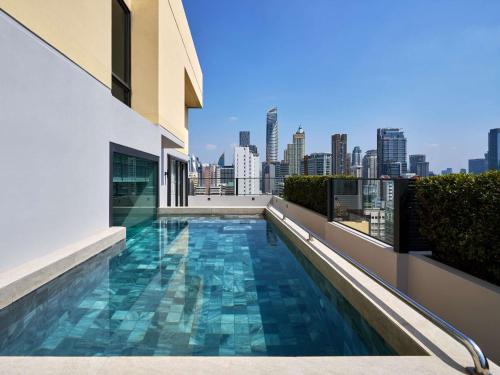 a swimming pool on the roof of a building with a city skyline at Novotel Bangkok on Siam Square in Bangkok
