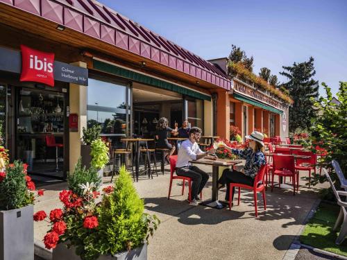 two people sitting at a table outside of a restaurant at ibis Colmar Est - Hotel Restaurant en Alsace in Colmar