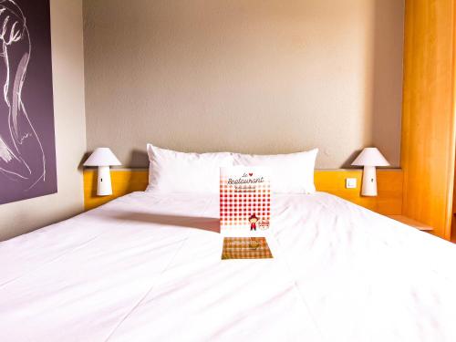 a bedroom with a bed with a book on it at ibis Colmar Est - Hotel Restaurant en Alsace in Colmar