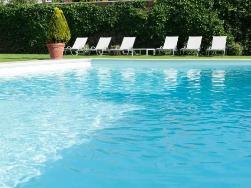 a group of chairs sitting next to a swimming pool at Novotel Brugge Centrum in Bruges