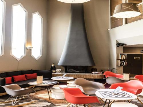 a living room with tables and chairs and a fireplace at Ibis Château-Thierry in Essômes-sur-Marne