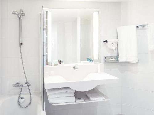 a white bathroom with a sink and a shower at Novotel Porto Gaia in Vila Nova de Gaia