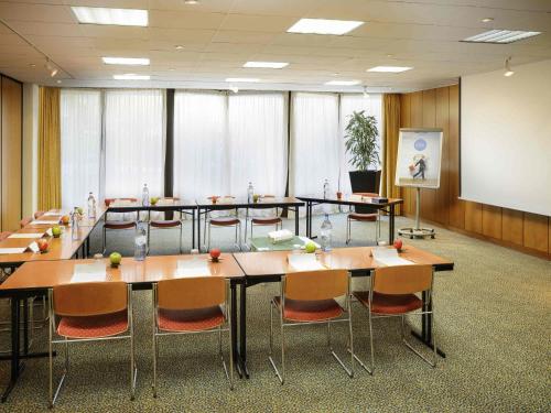 a conference room with tables and chairs and a screen at Novotel Porto Gaia in Vila Nova de Gaia