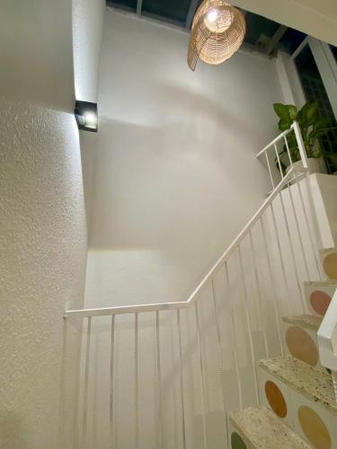 a white staircase with a white wall and a light at Homestay NAD nguyên căn tại Phan Thiết in Ấp Sung Xuân