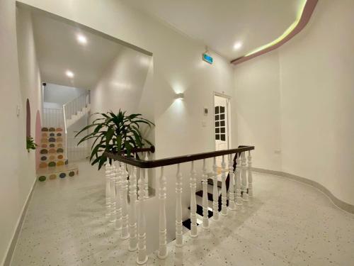 a white staircase with a wooden rail and a plant at Homestay NAD nguyên căn tại Phan Thiết in Ấp Sung Xuân