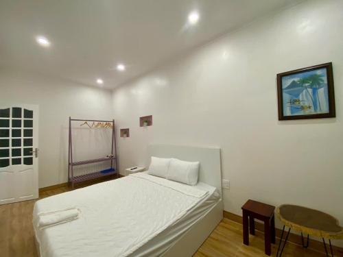 a white bedroom with a bed and a chair at Homestay NAD nguyên căn tại Phan Thiết in Ấp Sung Xuân
