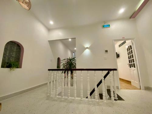 a staircase in a white room with a plant at Homestay NAD nguyên căn tại Phan Thiết in Ấp Sung Xuân