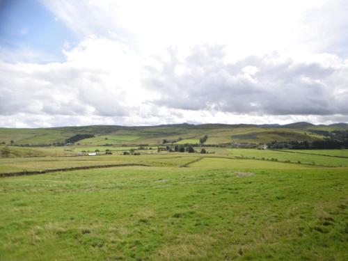 a field of green grass with hills in the background at 1 Bed in Teviothead 75346 in Hawick